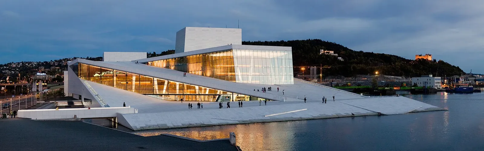 L'opéra d'Oslo et ses toits de marbre blanc inclinés, éclairé au crépuscule au bord de l'eau du fjord